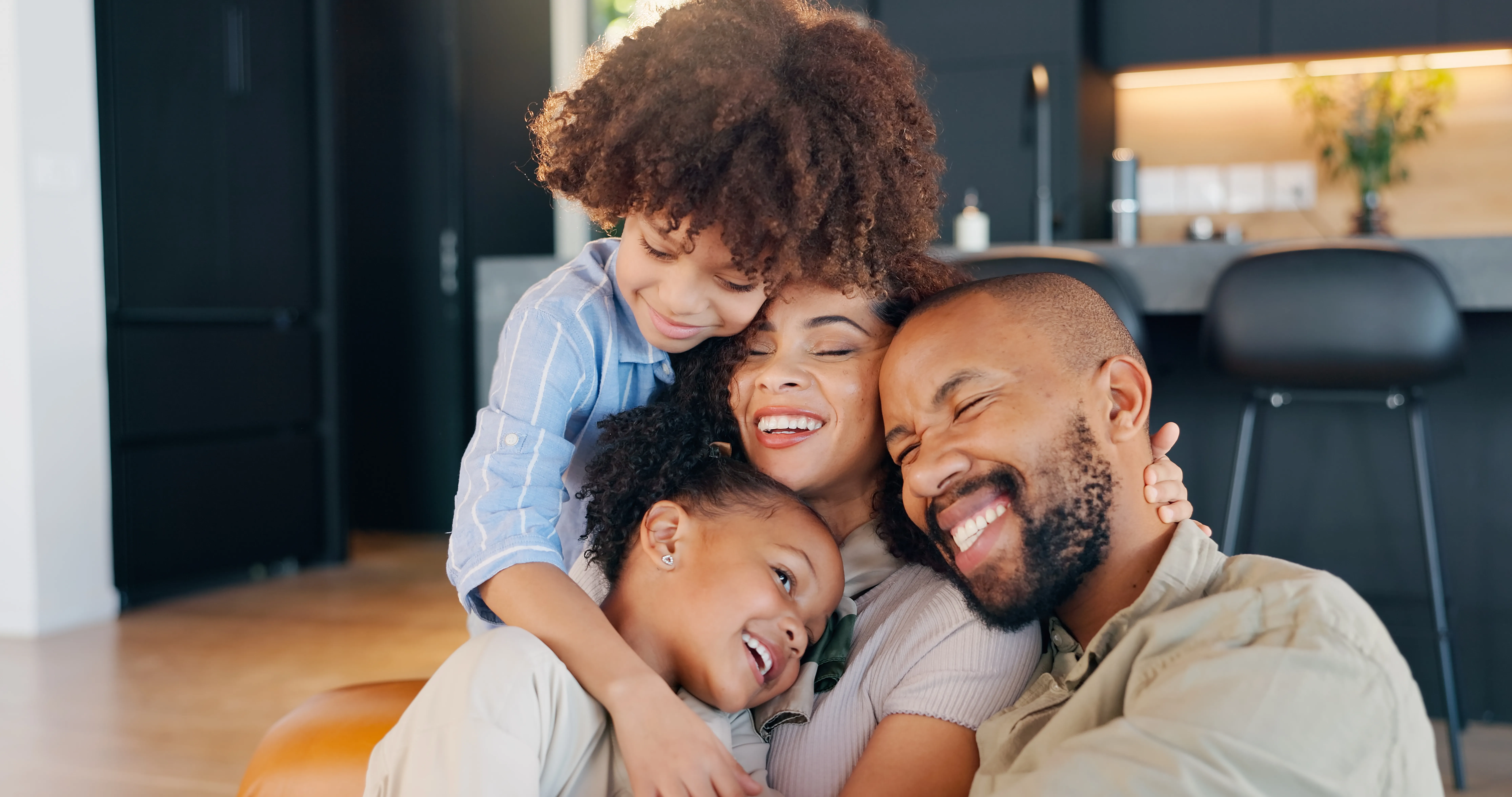 A family of four sharing a warm hug at home